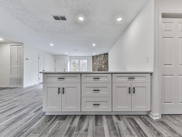 kitchen with white cabinets, a textured ceiling, and hardwood / wood-style flooring