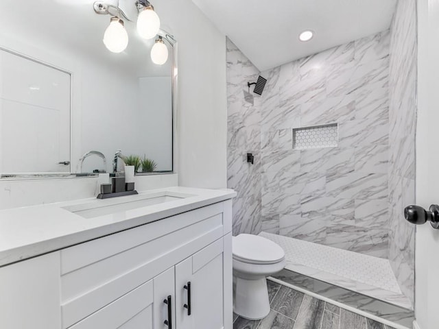 bathroom featuring tiled shower, vanity, and toilet