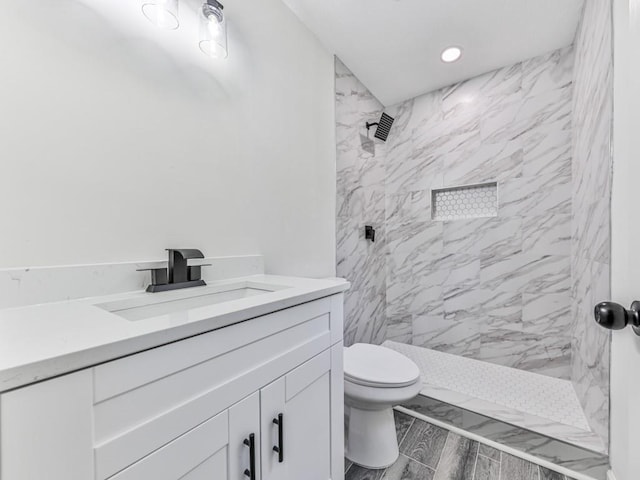 bathroom featuring tiled shower, vanity, and toilet