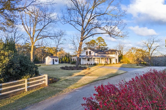 view of front of property featuring a front yard and a storage shed