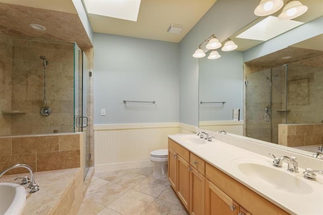 full bathroom with independent shower and bath, toilet, a skylight, tile patterned flooring, and vanity