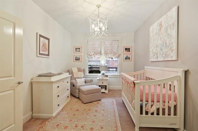 bedroom with light colored carpet, a nursery area, and a chandelier