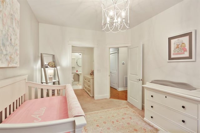 bedroom with a crib, a chandelier, and ensuite bathroom