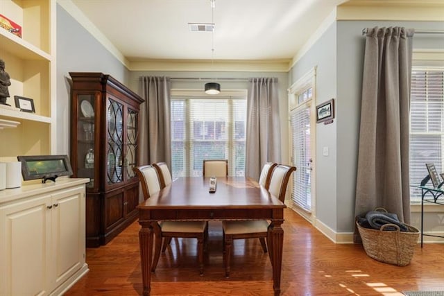 dining space featuring crown molding, built in shelves, and dark hardwood / wood-style floors