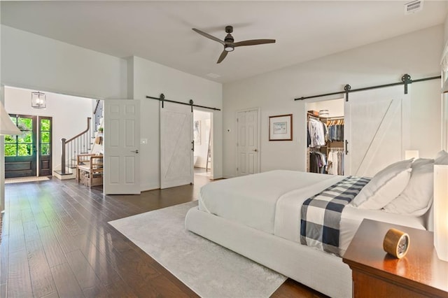 410 Longwood Ln, Alpharetta, GA 30004 - bedroom featuring a barn door, dark wood-style flooring, a spacious closet, and a ceiling fan
