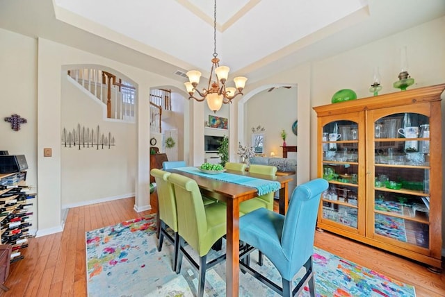 dining area featuring visible vents, baseboards, an inviting chandelier, arched walkways, and light wood-type flooring