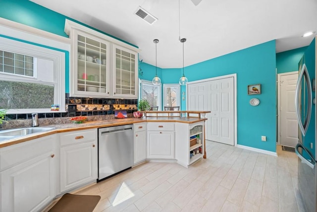 kitchen with visible vents, a sink, appliances with stainless steel finishes, a peninsula, and white cabinets