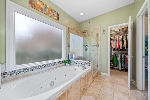 full bath featuring a spacious closet, a tub with jets, and a stall shower