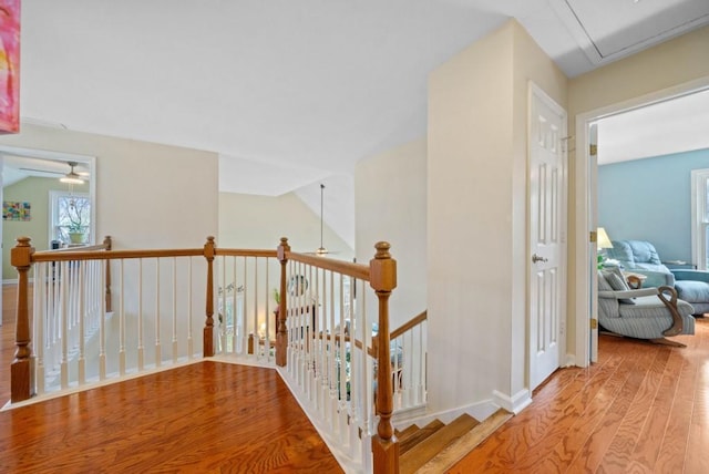 corridor featuring lofted ceiling, an upstairs landing, wood finished floors, and baseboards