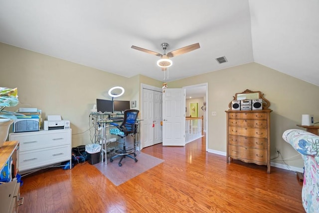 office with visible vents, light wood finished floors, baseboards, ceiling fan, and vaulted ceiling