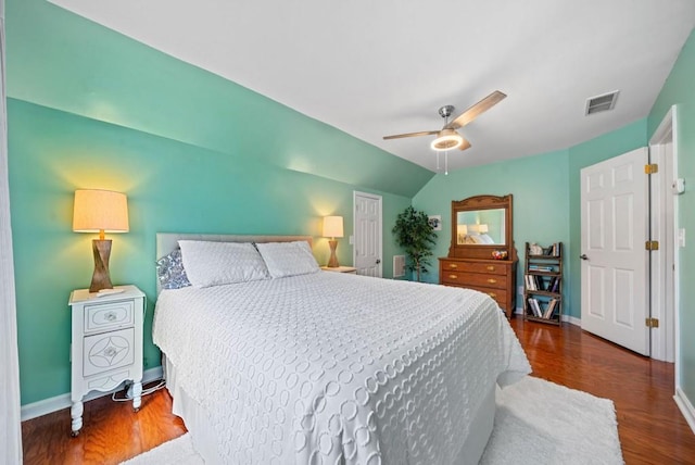 bedroom with lofted ceiling, wood finished floors, visible vents, and baseboards