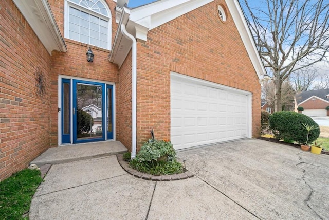 entrance to property featuring brick siding, driveway, and a garage