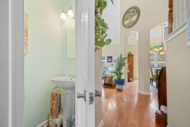 bathroom featuring hardwood / wood-style floors, a notable chandelier, baseboards, and a sink