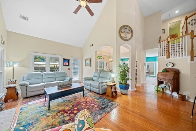 living area with visible vents, a ceiling fan, hardwood / wood-style flooring, arched walkways, and baseboards