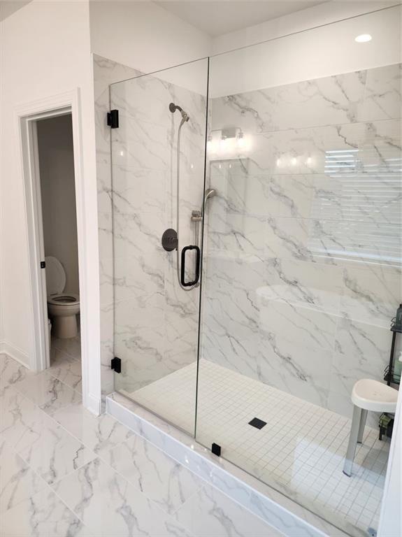 2949 Longbush, Duluth, GA 30097 - bathroom featuring a marble finish shower, marble look tiles, toilet, and baseboards