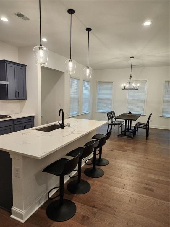 2949 Longbush, Duluth, GA 30097 - kitchen with stainless steel gas cooktop, dark wood-style flooring, a sink, a kitchen bar, and decorative light fixtures