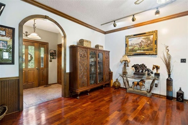 interior space with a textured ceiling, crown molding, and dark hardwood / wood-style flooring