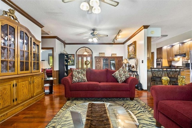 living room featuring a textured ceiling, ornamental molding, dark hardwood / wood-style floors, and ceiling fan