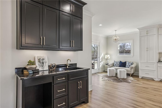 bar with baseboards, recessed lighting, ornamental molding, a sink, and light wood-style floors