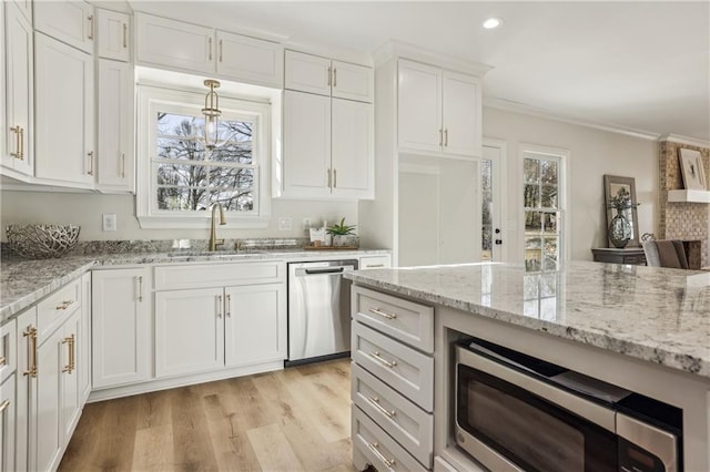 kitchen featuring light wood-style flooring, a sink, appliances with stainless steel finishes, white cabinetry, and crown molding