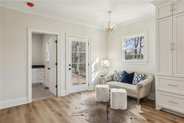 sitting room with a chandelier, light wood-style flooring, crown molding, and baseboards