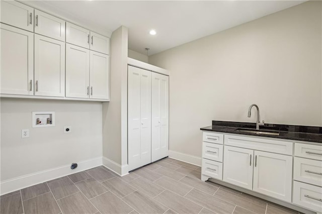 laundry area featuring baseboards, hookup for a washing machine, cabinet space, electric dryer hookup, and a sink