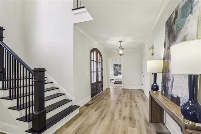 foyer entrance featuring stairs, crown molding, baseboards, and wood finished floors