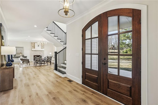 entrance foyer featuring stairway, ornamental molding, french doors, a notable chandelier, and light wood-type flooring