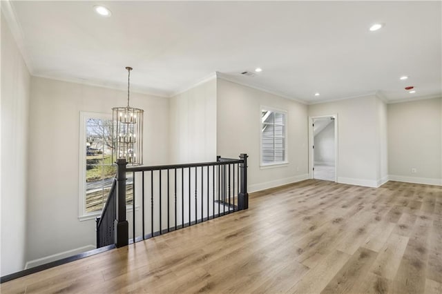 spare room with light wood-type flooring, baseboards, an inviting chandelier, and visible vents