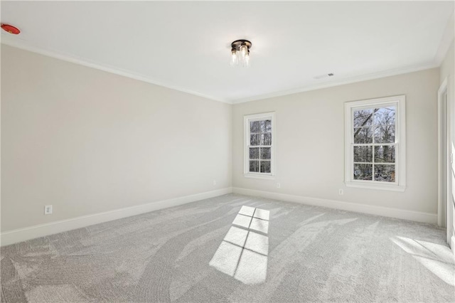 carpeted spare room with plenty of natural light, visible vents, crown molding, and baseboards