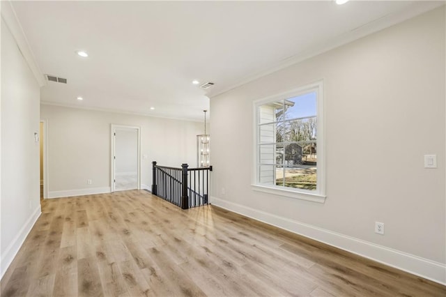 spare room featuring visible vents, baseboards, light wood-style floors, and crown molding