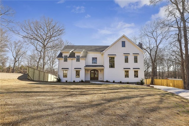 modern inspired farmhouse with a front lawn, fence, french doors, board and batten siding, and a chimney