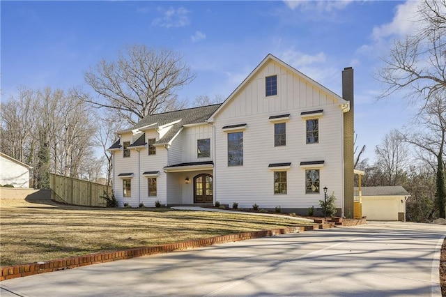 modern farmhouse with an outdoor structure, a garage, board and batten siding, and a chimney