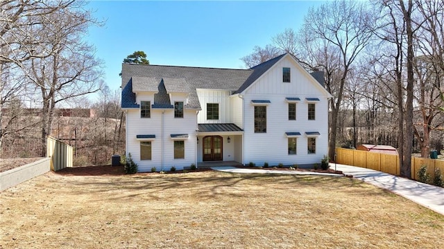 modern farmhouse style home with board and batten siding, fence, cooling unit, metal roof, and a standing seam roof