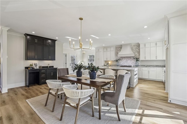 dining space featuring recessed lighting, light wood-type flooring, an inviting chandelier, and crown molding