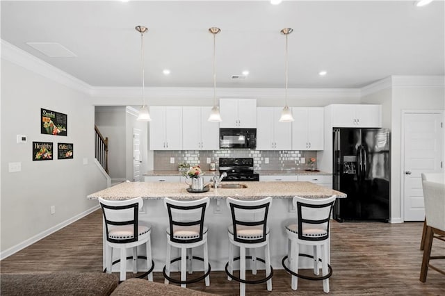 kitchen featuring pendant lighting, black appliances, and a center island with sink