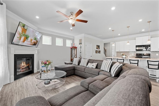 living room featuring ornamental molding, ceiling fan, and light hardwood / wood-style flooring