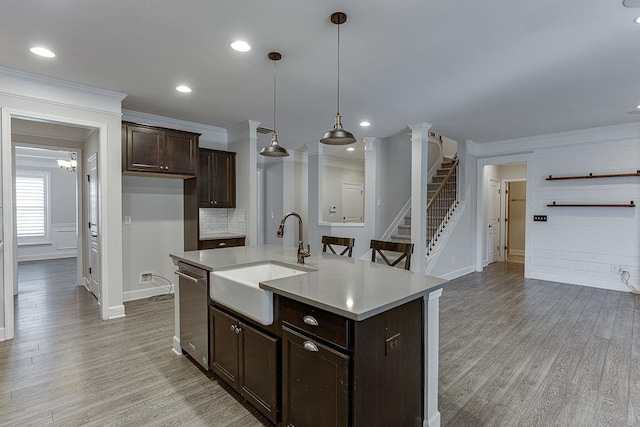 kitchen with crown molding, dark brown cabinetry, light countertops, light wood-style flooring, and a sink