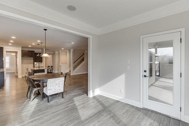 dining area featuring stairway, light wood-style flooring, crown molding, and baseboards