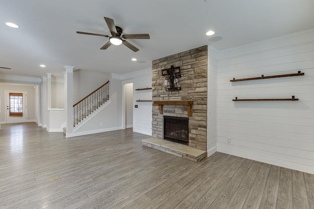 unfurnished living room with a ceiling fan, wood finished floors, stairway, a fireplace, and crown molding