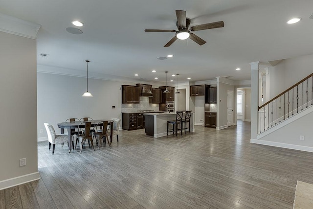 dining space with wood finished floors, crown molding, a ceiling fan, and baseboards