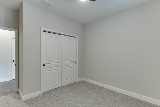 unfurnished bedroom featuring visible vents, baseboards, light colored carpet, and a closet