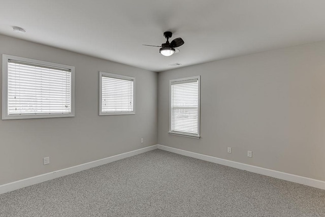 empty room with visible vents, light colored carpet, baseboards, and a ceiling fan