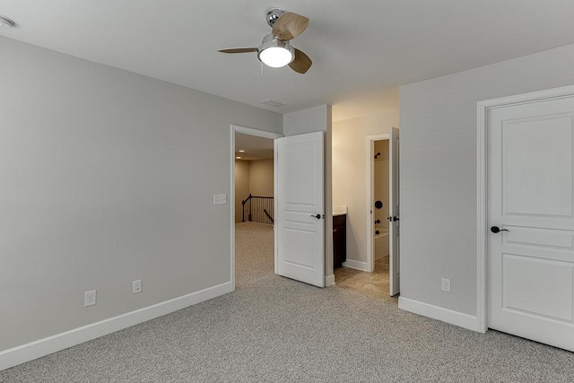 unfurnished bedroom with connected bathroom, baseboards, light colored carpet, and ceiling fan