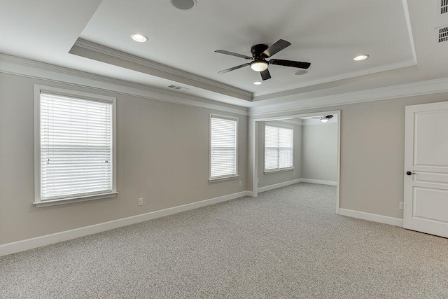 spare room with visible vents, baseboards, a tray ceiling, light carpet, and a ceiling fan