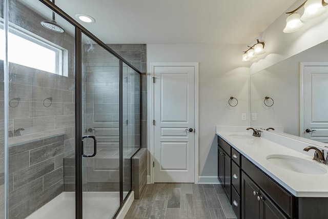 bathroom with double vanity, a stall shower, and a sink