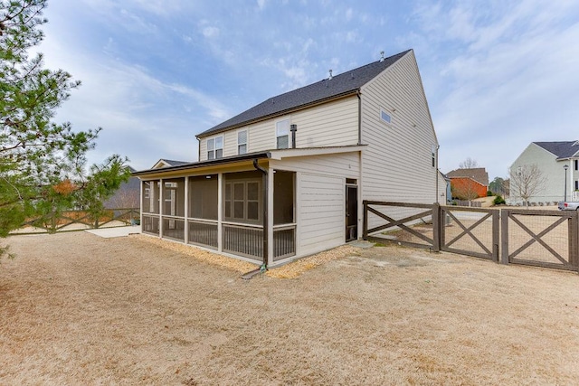 back of property with fence, a sunroom, and a gate