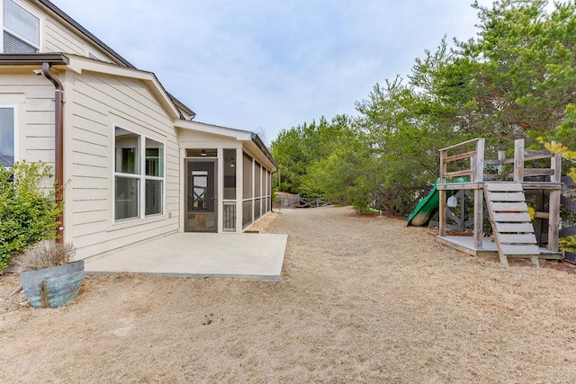 view of yard featuring a patio area, a playground, and a sunroom