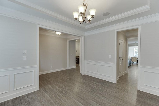 unfurnished room featuring a decorative wall, ornamental molding, wood finished floors, and a chandelier