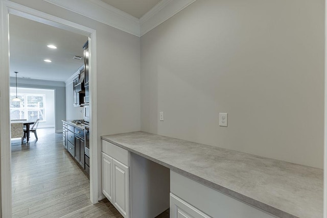 kitchen featuring light countertops, light wood-type flooring, ornamental molding, recessed lighting, and white cabinets